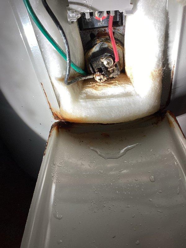Responded to service call for Bradford White electric water heater (Model: RD250T6-1NCWWSerial: XD47671879) experiencing hot water loss during use. Upon arrival, performed diagnostic inspection of 5-6 year old unit. Removed access panel and discovered wet insulation with extensive rust staining throughout electrical compartment. Found evidence of moisture intrusion around upper electrical connections with significant corrosion present on metal surfaces and electrical housing assembly. Observed water pooling in internal pan and rust discoloration on vertical and horizontal surfaces surrounding wiring terminals. 

Customer reported intermittent hot water failure approximately 7 minutes into shower usage and noted previous signs of water running down front of unit, though exterior was dry at time of inspection. Documented extensive internal corrosion via photographic evidence showing compromised condition of electrical connection assembly and surrounding components. Evaluated overall unit