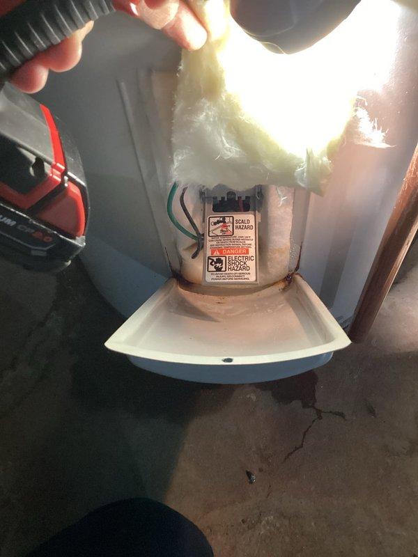 Responded to service call for Bradford White electric water heater (Model: RD250T6-1NCWWSerial: XD47671879) experiencing hot water loss during use. Upon arrival, performed diagnostic inspection of 5-6 year old unit. Removed access panel and discovered wet insulation with extensive rust staining throughout electrical compartment. Found evidence of moisture intrusion around upper electrical connections with significant corrosion present on metal surfaces and electrical housing assembly. Observed water pooling in internal pan and rust discoloration on vertical and horizontal surfaces surrounding wiring terminals. 

Customer reported intermittent hot water failure approximately 7 minutes into shower usage and noted previous signs of water running down front of unit, though exterior was dry at time of inspection. Documented extensive internal corrosion via photographic evidence showing compromised condition of electrical connection assembly and surrounding components. Evaluated overall unit