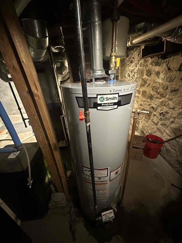 Installed new AO Smith ProLine 40-gallon natural gas water heater (Model GCV 40 410) in basement utility area. Unit was properly positioned, connected to existing gas and water supply lines with copper piping, and vented through metallic ductwork per manufacturer specifications and local building codes.