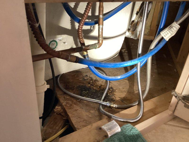 Responded to water leak in basement bathroom. Upon inspection, identified active leak originating from water heater supply line connections. Found deteriorated flexible connector with visible water damage to surrounding flooring and carpet. Shut off water supply to affected fixture, replaced failed braided stainless steel supply line, and tested all connections for proper seal. Verified no additional leaks present and restored water service to unit.