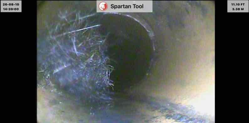 Responded to basement drain backup affecting laundry, shower, and toilet fixtures on municipal sewer system. Performed video camera inspection of main drain line, identifying significant obstruction at 11.10 feet consisting of fibrous debris and tangled material, with additional blockage discovered at 22.30 feet showing accumulated buildup on pipe walls. Successfully cleared main drain cleanout, removing obstructions and restoring proper drainage flow throughout the system.