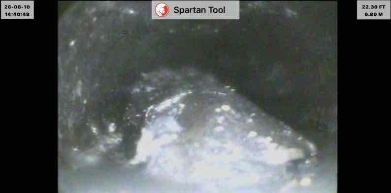 Responded to basement drain backup affecting laundry, shower, and toilet fixtures on municipal sewer system. Performed video camera inspection of main drain line, identifying significant obstruction at 11.10 feet consisting of fibrous debris and tangled material, with additional blockage discovered at 22.30 feet showing accumulated buildup on pipe walls. Successfully cleared main drain cleanout, removing obstructions and restoring proper drainage flow throughout the system.