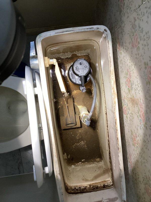 Responded to service call for leaking toilet. Upon inspection, found significant mineral buildup and sediment accumulation in tank affecting flush valve operation. Removed tank lid and assessed internal components including pressure-assisted flush mechanism, fill valve assembly, and associated hardware. Identified deteriorated tank components and mineral deposits as source of leak. Cleaned internal surfaces, replaced faulty flush valve assembly and fill valve components, and verified proper water level adjustment. Tested flush operation multiple times to confirm leak was resolved and all components functioning correctly. Left fixture in proper working order with no active leaks detected.