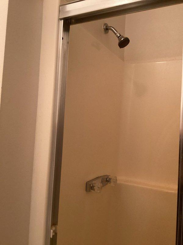Completed faucet change-out in mobile home-style kitchen installation. Accessed plumbing through wall panel opening, exposing copper supply lines secured with plastic mounting clips against waterproofing material and wooden framing. Removed existing traditional faucet and installed replacement unit per specifications, verifying proper water flow and connection integrity upon completion.