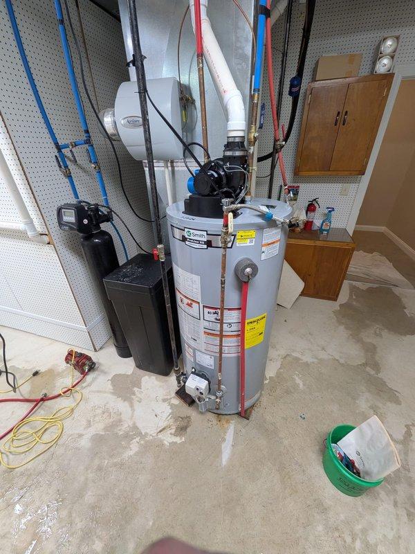 Responded to water leak emergency and completed water heater replacement in residential utility room. Protected hardwood flooring throughout work area with multiple tarps to prevent water damage during installation. Removed existing failed water heater and installed new residential tank-type water heater per previously approved specifications. Connected unit to existing copper supply lines and PEX distribution piping. Integrated installation with existing water treatment system including black filtration unit and expansion tank. Secured all pipe connections with appropriate fittings and clamps, tested system for proper operation and verified no leaks at connection points. Cleaned work area and removed old equipment and debris upon completion.