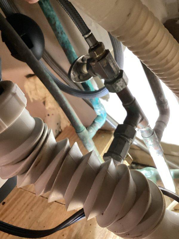 Responded to emergency water leak involving refrigerator supply line located beneath kitchen sink. Upon arrival, confirmed main water supply to home was shut off and standing water was present. Investigated shutoff valve under sink which had failed to isolate the refrigerator line. Inspected plumbing connections, refrigerant lines, and associated HVAC components in the affected area. Documented existing conditions including aged PVC piping with visible discoloration, flexible supply lines, and mechanical connections. Assessed water damage to surrounding surfaces and verified leak source at refrigerator water line connection point.