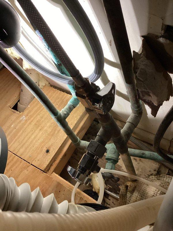Responded to emergency water leak involving refrigerator supply line located beneath kitchen sink. Upon arrival, confirmed main water supply to home was shut off and standing water was present. Investigated shutoff valve under sink which had failed to isolate the refrigerator line. Inspected plumbing connections, refrigerant lines, and associated HVAC components in the affected area. Documented existing conditions including aged PVC piping with visible discoloration, flexible supply lines, and mechanical connections. Assessed water damage to surrounding surfaces and verified leak source at refrigerator water line connection point.