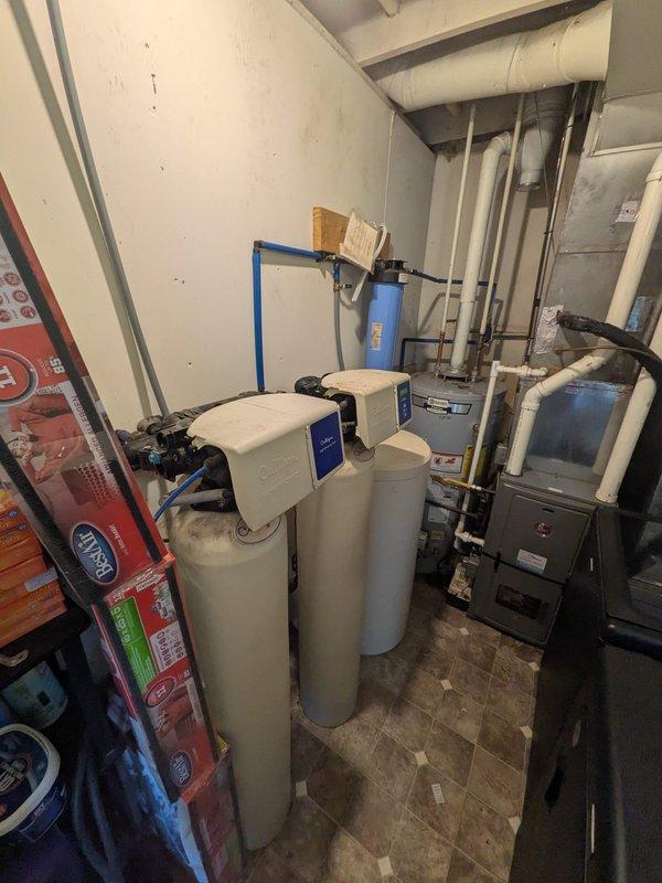 Responded to service call for 7-year-old Culligan water softener not consuming salt properly, indicating system malfunction. Performed comprehensive inspection of water treatment system in basement mechanical room, examining twin water softener tanks with blue control valves and associated plumbing connections. Assessed unit operation, control valve functionality, salt bridge formation, and brine tank operation to diagnose cause of improper regeneration cycle.