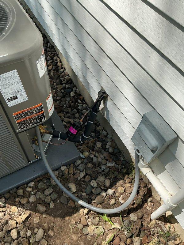 # HVAC System Replacement

Successfully completed a full residential air conditioning system replacement. Removed existing equipment and installed a new Lennox ML13KC-024-230 condenser unit positioned on a stable base against the exterior wall with proper clearances. The outdoor unit was mounted on dark-colored platform with refrigerant lines routed through gray flexible conduit across decorative river rock landscaping. White PVC condensate drainage piping was installed with appropriate elbows and fittings for proper system drainage.

Inside the residence, installed a new Lennox CK40DT-24A-71 furnace unit in the utility space. Connected galvanized steel ductwork to the furnace with proper transitions running vertically and horizontally for air distribution. Routed yellow gas supply line along the wall with secure mounting and proper connection to the furnace gas valve. Installed insulated copper refrigerant lines connecting the indoor and outdoor units. Mounted electrical control compo