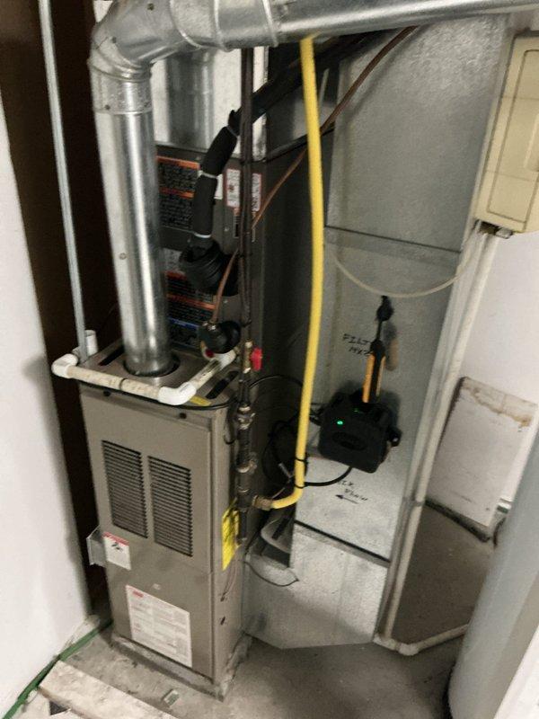 # HVAC System Replacement

Successfully completed a full residential air conditioning system replacement. Removed existing equipment and installed a new Lennox ML13KC-024-230 condenser unit positioned on a stable base against the exterior wall with proper clearances. The outdoor unit was mounted on dark-colored platform with refrigerant lines routed through gray flexible conduit across decorative river rock landscaping. White PVC condensate drainage piping was installed with appropriate elbows and fittings for proper system drainage.

Inside the residence, installed a new Lennox CK40DT-24A-71 furnace unit in the utility space. Connected galvanized steel ductwork to the furnace with proper transitions running vertically and horizontally for air distribution. Routed yellow gas supply line along the wall with secure mounting and proper connection to the furnace gas valve. Installed insulated copper refrigerant lines connecting the indoor and outdoor units. Mounted electrical control compo