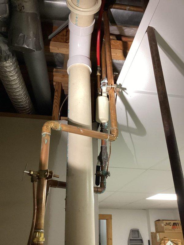 Responded to water leak in lower level basement utility area. Upon arrival, identified active leak from damaged pipe connected to water heater with customer-placed bucket collecting water. Inspected water heater plumbing assembly including copper supply lines, PEX distribution lines, and associated fittings. Documented compromised pipe section with hole causing water discharge. Assessed surrounding plumbing infrastructure including PVC drainage system, gas connections, and mounting hardware for additional concerns. Photographed affected area showing water heater, furnace, and complete piping configuration for repair documentation and customer records.