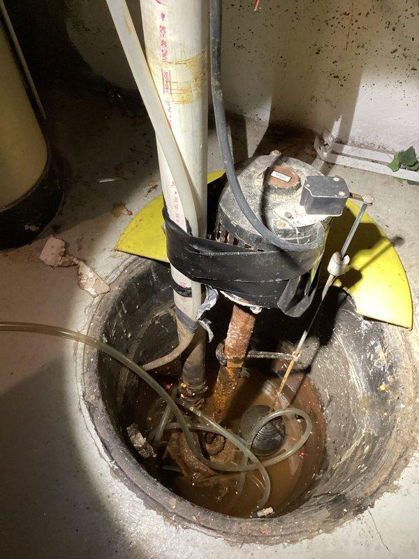 Responded to a non-operational groundwater sump pump in basement. Upon inspection, found sump pit filled with discolored water to an elevated level, indicating pump failure during an extended period when the property was unoccupied for approximately six weeks. Examined the sump pump assembly and associated discharge piping system, which included multiple PVC pipes and connections. Noted significant corrosion and rust on copper components submerged in the basin, suggesting extended exposure to water and potential contributing factor to system failure. No tripped breakers were identified during initial assessment. Documented existing conditions through photographs showing the failed pump assembly, deteriorated mechanical components, water accumulation in the pit, and evidence of moisture-related damage to surrounding concrete floor and wooden structural elements. The float switch mechanism and pump motor showed no response when tested. Provided detailed findings documentation for insuran
