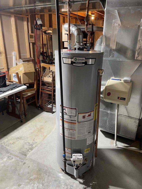 Completed installation of 40-gallon A.O. Smith natural gas water heater (Model GCR-40 410) in basement utility area. Unit was properly positioned on concrete floor, connected to existing copper supply lines and overhead plumbing systems, and integrated with HVAC infrastructure in residential setting.