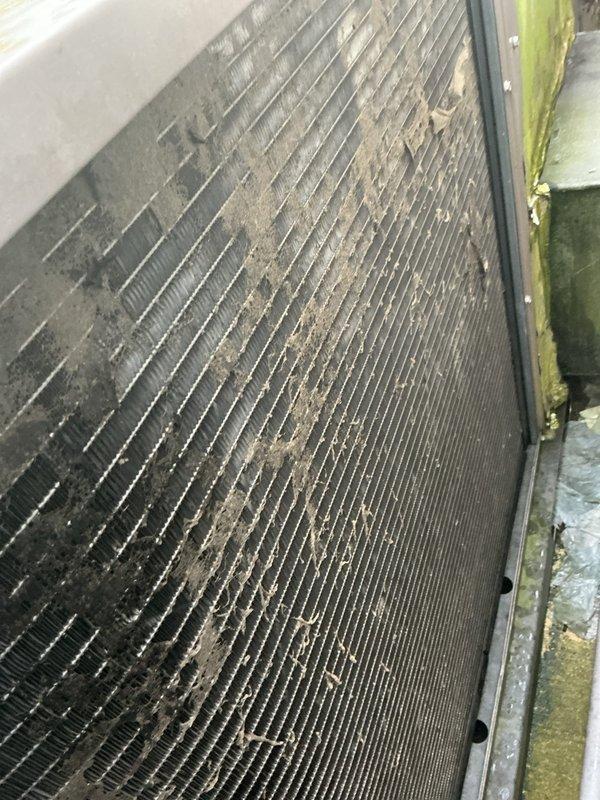 Responded to no-cooling complaint on residential air conditioning system approximately 10 years old with airflow present but warm air discharge. Upon inspection, discovered severely contaminated condenser coils with heavy accumulation of dirt, dust, and debris restricting airflow and heat transfer capability. Thoroughly cleaned condenser coil fins to restore proper heat exchange function and system efficiency. System tested and verified returning to normal cooling operation following coil cleaning procedure.