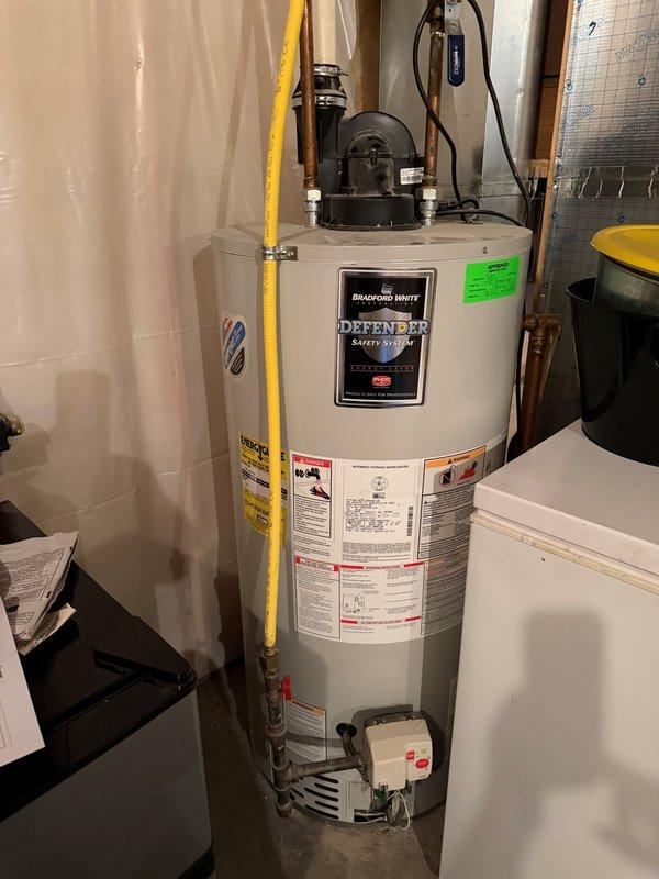 Completed installation of Bradford White Defender Safety System tanked water heater in residential basement utility area. Removed existing unit and installed new water heater in drain pan with proper drainage piping to floor drain as specified. Connected all copper supply and discharge lines, installed yellow flexible gas line with appropriate fittings, and completed electrical connections. Replaced grinder pump as part of scope of work. Verified all plumbing connections for leaks, tested gas connections for safety, and confirmed proper operation of new water heater and safety systems. Protected work area with tarps during two-flight stair access to prevent damage to interior surfaces. All installations meet code requirements and manufacturer specifications.