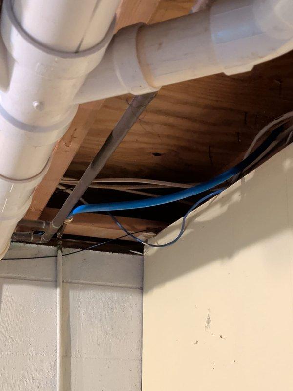 Responded to service call for refrigerator ice maker water line issue and main drain line concerns. Inspected main drain line system showing signs of corrosion and potential structural concerns requiring access through ceiling/wall opening. Assessed exposed plumbing infrastructure including PVC drainage piping and support brackets to determine condition and necessary corrective measures.