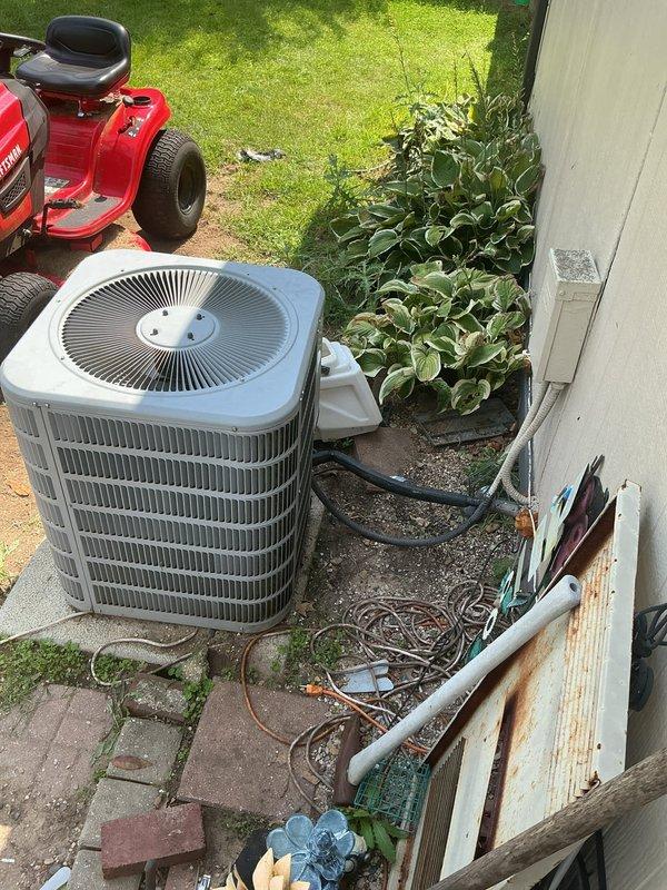 Completed residential furnace installation in basement location accessed via interior staircase. New HVAC system integrated with existing outdoor condenser unit positioned on concrete pad adjacent to building exterior. All equipment properly connected, tested, and verified operational per manufacturer specifications.