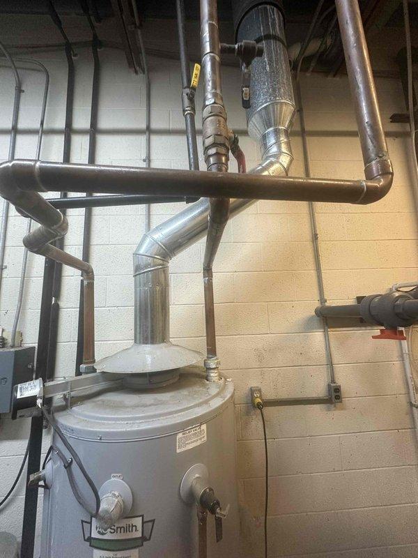 Completed on-site evaluation of existing commercial gas-fired tank-type water heater installation in mechanical room. Assessed A.O. Smith water heater unit, including examination of gas supply connections, venting configuration, and surrounding plumbing infrastructure. Documented existing copper piping network, metallic ductwork, and ventilation systems connected to the unit. Photographed water heater controls, valves, manufacturer specifications, and overall installation layout including electrical panels and utility connections to provide comprehensive estimate for replacement or service requirements.