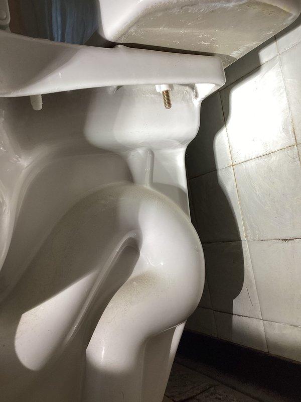 Responded to upstairs bathroom for reported toilet leaking at base. Upon inspection, identified water seepage around the toilet base indicating a compromised wax ring seal. Documented existing conditions including moisture presence and interior bowl staining. Assessed toilet mounting, supply line connections, and floor flange integrity to determine proper repair approach for resolving the leak.