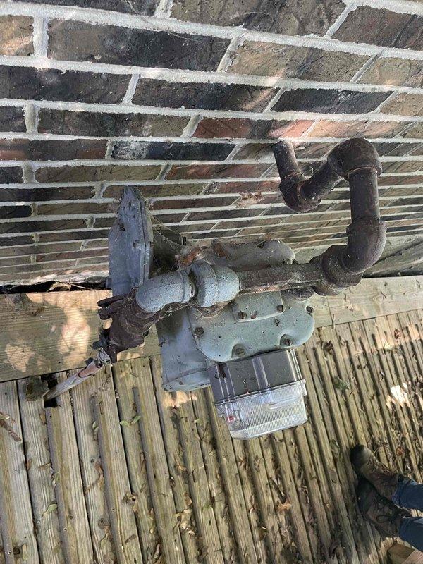 Performed site inspection to assess natural gas line installation requirements from existing meter location at house to detached garage approximately 110 feet away. Evaluated current gas meter assembly mounted on exterior brick wall, noting existing pipe configuration and connection points. Assessed routing path across property to determine optimal trench location, accounting for obstacles and grade changes. Inspected garage interior construction and wall composition to plan proper termination point and interior rough-in requirements. Documented existing conditions with photographs for estimate preparation, including current meter setup and proposed endpoint location in storage structure.