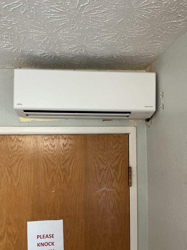 Installed Fujitsu Airstage mini-split system in room 107, including indoor wall-mounted air handler and outdoor condensing unit mounted on brick exterior. Completed full system startup, verified refrigerant charge using digital manifold gauges, and performed all operational checks to ensure proper system function and performance parameters were met.