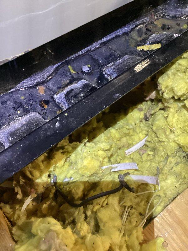 Responded to report of lingering leak at outdoor unit location where previous secondary catch pan installation was insufficient. Inspected attic space and located hallway HVAC unit with inadequate condensate containment system. Documented existing conditions showing improperly sized catch pans that did not extend to full equipment footprint, allowing water to bypass containment during condensate overflow events. Verified active moisture issues in surrounding insulation and structural components. Photographed metal mounting brackets, insulation damage, and HVAC equipment positioning to document extent of water intrusion and inadequate secondary drain pan coverage requiring corrective action.