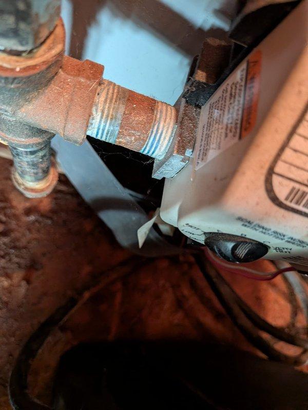 Responded to service call for progressively declining water pressure and intermittent leak in garage area near water softener and water heater. Upon inspection, discovered severe corrosion on water heater tank and associated plumbing connections, with extensive rust accumulation on threaded pipe fittings and metal surfaces indicating prolonged moisture exposure. The corroded components and deteriorated fittings were identified as the source of both the pressure loss and the random leaking pattern reported by the homeowner. Documented existing conditions showing advanced oxidation on copper fittings, compromised tank integrity, and aging infrastructure requiring immediate attention to restore proper water pressure and eliminate leak source.