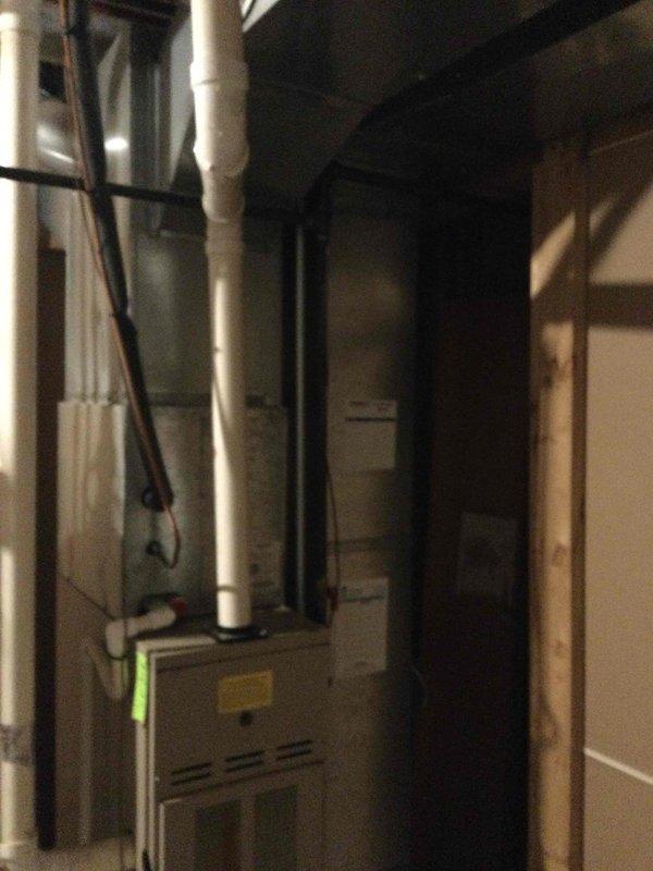 Performed comprehensive evaluation of 26-year-old HVAC system for replacement estimate. Conducted multi-point safety inspection including CO detection, gas leak check, and electrical system assessment on operational furnace and air conditioning equipment. Documented existing gray metal furnace unit in basement mechanical room with white PVC venting system and outdoor tan/beige cylindrical condenser unit with black protective grille mounted on concrete pad against exterior wall. System confirmed operational and ready for replacement quote preparation.