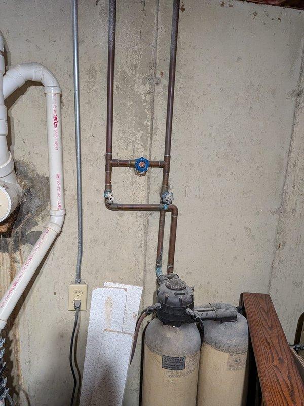 Responded to service call for broken cold water shut-off valve with minimal leaking. Upon arrival, inspected plumbing system in basement utility area and confirmed the shut-off valve lever had broken off, rendering the valve inoperable. Assessed the copper piping configuration, water filtration system tanks, and associated plumbing connections for any additional damage or concerns. Replaced the defective shut-off valve with new chrome-plated quarter-turn shut-off valve, ensuring proper connection to existing copper supply lines. Tested the new valve for proper operation and verified no active leaks were present. Confirmed water supply was restored and shut-off functionality was operational for future use.