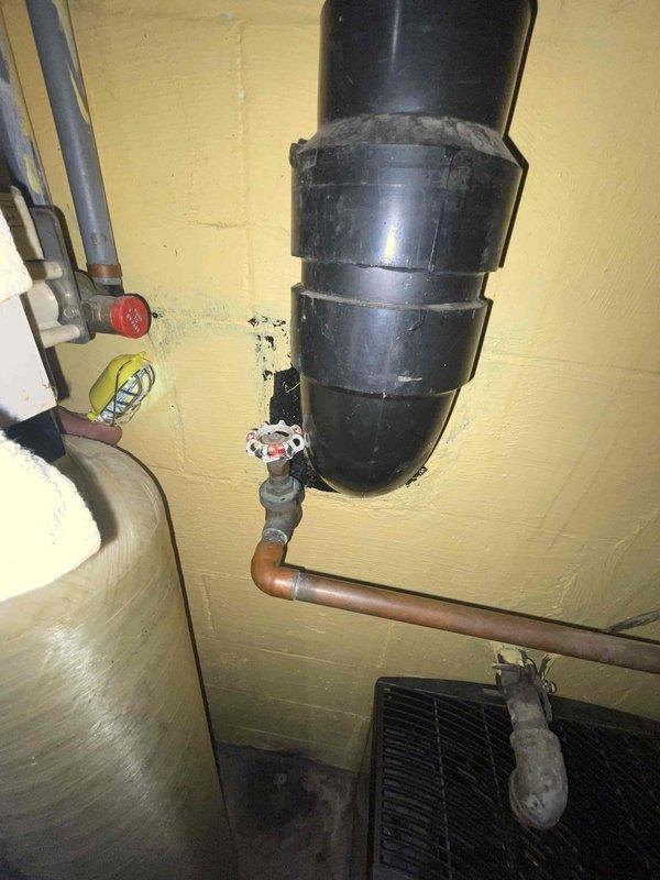 Responded to basement water leak complaint and performed diagnostic inspection of plumbing system. Located active leak at aged brass valve assembly connected to copper piping near water heater. Valve body showed significant corrosion and deterioration at threaded connections, with visible oxidation on copper supply lines. Inspected surrounding plumbing infrastructure including horizontal copper runs, PVC drainage system, and shut-off valves to assess overall system condition and identify source of leak. Documented plumbing configuration and leak location with photographs for repair recommendations.
