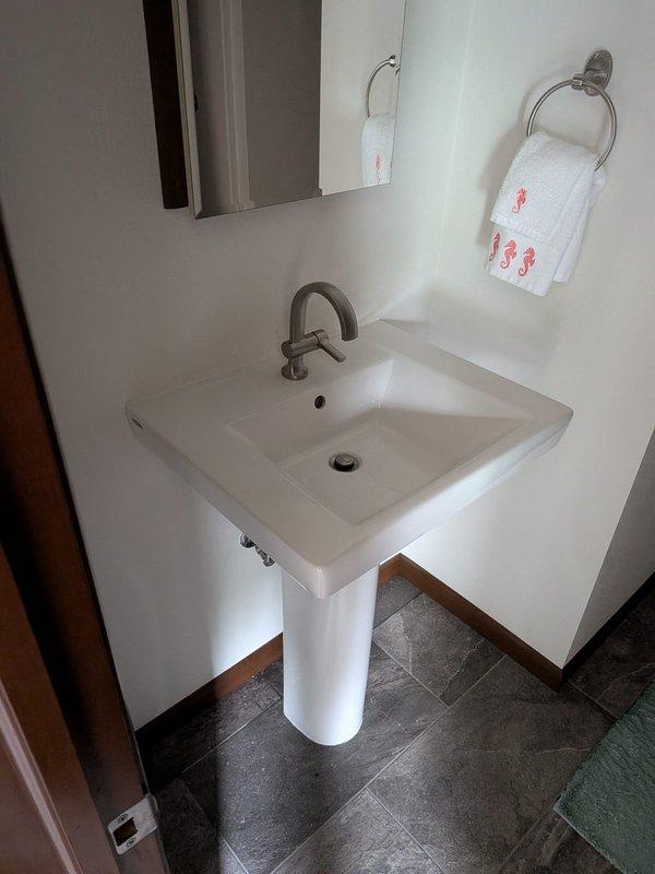 Replaced Delta single-handle faucet on pedestal sink in bathroom. Successfully accessed wall-mounted supply lines and connections without damaging wall surface or creating visible openings. Completed installation with chrome shut-off valve and braided supply line, ensuring proper water flow and leak-free operation.