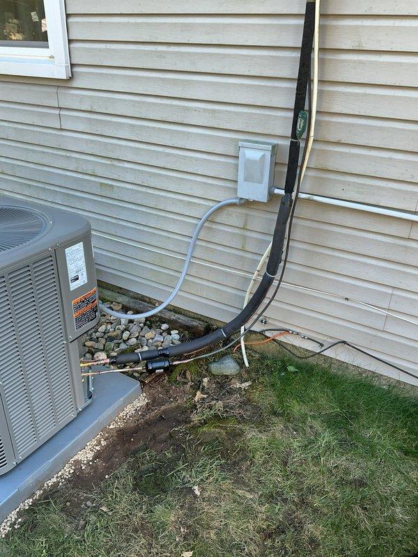 Completed full HVAC system installation including ML180UH070E36A furnace, ML13KC1-024 condenser unit, CK40CT-24A evaporator coil, and S200 thermostat. Positioned outdoor condensing unit on concrete pad with proper clearances from structure, installed electrical disconnect box and conduit routing to exterior wall, and ran refrigerant lines and drain piping from condenser to indoor air handler. Set up gravel base around outdoor unit for drainage and aesthetic finish, verified all electrical connections meet code requirements, and confirmed proper system operation with new digital thermostat control.
