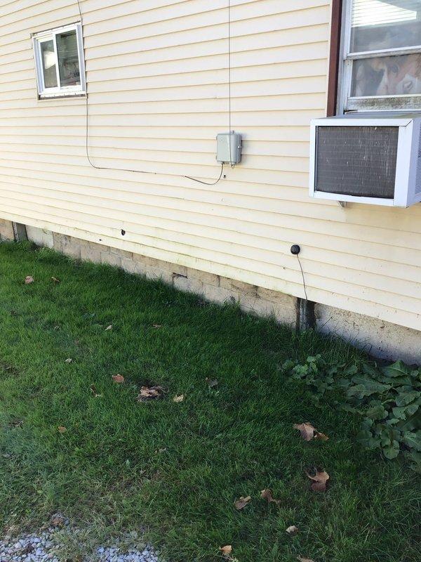 Conducted on-site evaluation for mini-split air conditioning system installation at residential property. Assessed existing electrical infrastructure and identified panel with evidence of heat damage and corrosion on lower breaker section, which will require remediation prior to new system installation. Evaluated exterior mounting location on yellow vinyl-sided wall where current window AC unit is installed, confirmed adequate space and structural support for outdoor condenser placement, and documented electrical junction box positioning for connection planning.