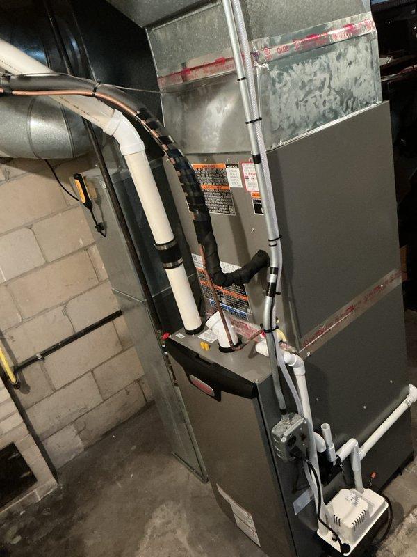 Completed full HVAC system installation in basement utility area, including EL297UH070XV36B furnace unit, ML13KC1-030-230 condenser, and CK40CT-30B-71-1610 evaporator coil with S200 thermostat. Installed all necessary metallic supply and return ductwork with proper transitions, white PVC condensate drainage and venting piping, and electrical connections. System tested and verified operational with all safety labels affixed and equipment secured to manufacturer specifications.