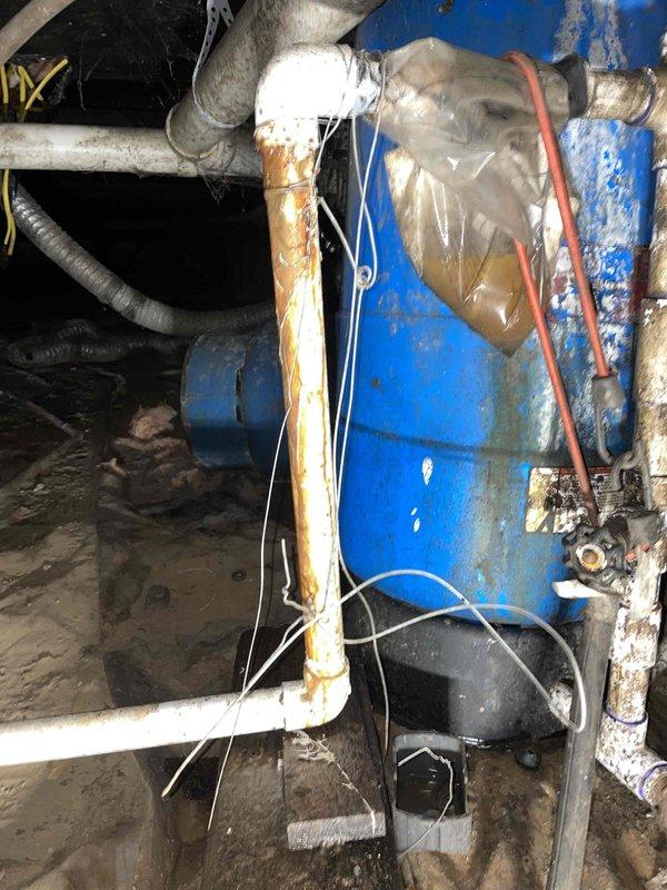 Responded to water leak in crawlspace on main inlet line from well pump to house. Upon arrival, inspected blue pressure tank and associated plumbing connections in confined crawlspace area. Located active leak on main inlet piping near pressure tank assembly. Equipment showed significant age and corrosion, with weathered blue pressure tank, corroded fittings, and deteriorated pipe connections. Documented leak location and condition of existing plumbing system including copper piping, PVC connections, and flexible hoses. Advised customer of repair requirements for inlet line and recommended water shutoff to prevent further water damage until permanent repairs could be completed.