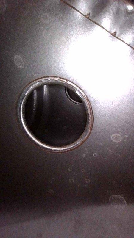 Performed a planned tune-up on the basement furnace, which had no reported issues and was last serviced in November of the previous year. Inspected the unit and photographed areas of concern, including corrosion and rust discoloration around a round opening in the metal housing and rough, uneven wear at a drain rim with debris in the opening. Recommend monitoring these corroded areas and scheduling follow-up evaluation if deterioration progresses.