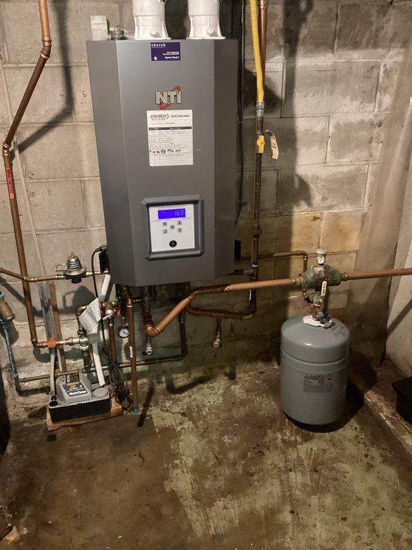 Replaced the existing expansion tank on the NTI wall-mounted boiler system with a new unit, installed upright on the hydronic loop and connected to the copper piping with a brass union and isolation valve. The installation was labeled and the system was left operational in the basement mechanical room.