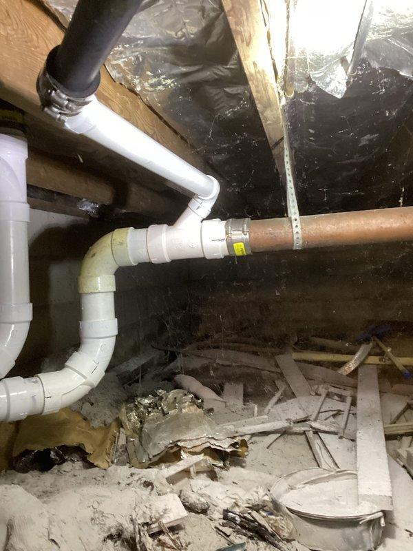 Removed the toilet and cut out the failed 3" copper drain line from the cast iron hub to the vent stack, then replaced it with new PVC drain piping and fittings. Relocated the tub drain connection in PVC and joined the new PVC to the existing cast iron and remaining copper using mechanical transition couplings with band clamps. Reset the toilet and pressure-tested the system to confirm leak-free operation.