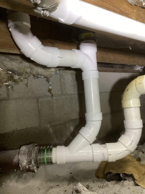 Removed the toilet and cut out the failed 3" copper drain line from the cast iron hub to the vent stack, then replaced it with new PVC drain piping and fittings. Relocated the tub drain connection in PVC and joined the new PVC to the existing cast iron and remaining copper using mechanical transition couplings with band clamps. Reset the toilet and pressure-tested the system to confirm leak-free operation.