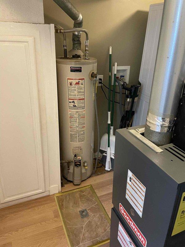 Performed diagnostic evaluation of an approximately 30-year-old gas-fired tank water heater for warranty assessment, with the main water supply found shut off. Inspection identified backflow from the water heater into the well system as the cause of pressure loss at the well tank, and the unit's age and condition were documented for coverage review.