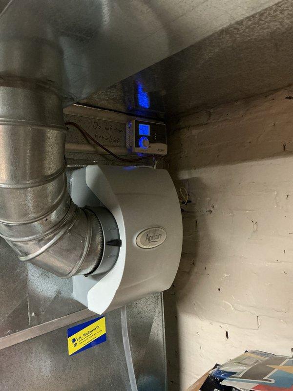 Completed warranty service call to install a humidistat for customer's Aprilaire humidifier system. Successfully mounted and connected the digital control panel with blue-lit display to the existing HVAC ductwork in basement area. System is now properly equipped with humidity control functionality as specified under original warranty terms.
