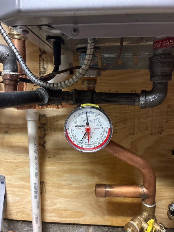 Completed boiler installation to resolve no-heat issue. Installed new circulator pump (007) with proper copper pipe connections and pressure gauge for system monitoring. Connected gas line with appropriate fittings and ensured all components were properly mounted to structural backing.
