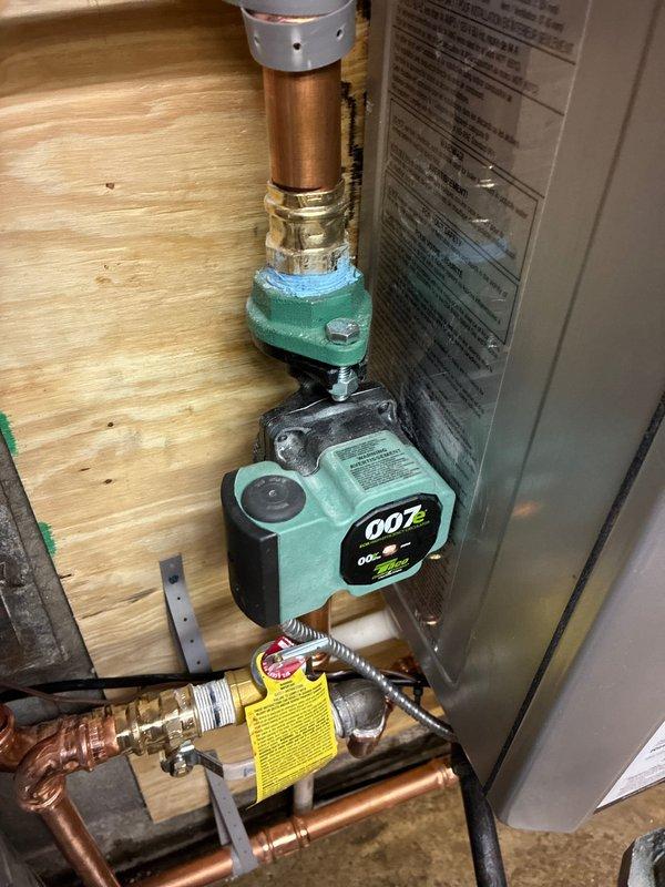 Completed boiler installation to resolve no-heat issue. Installed new circulator pump (007) with proper copper pipe connections and pressure gauge for system monitoring. Connected gas line with appropriate fittings and ensured all components were properly mounted to structural backing.