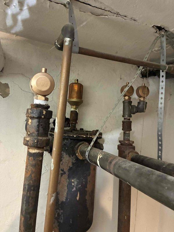Completed scheduled boiler maintenance service. Inspected system components including pressure gauges, valves, and pipe connections. Noted significant corrosion and rust on black metal components, particularly on central valve assembly, and wall deterioration around mounting hardware. Recommended replacement of deteriorated components to prevent future system failure.