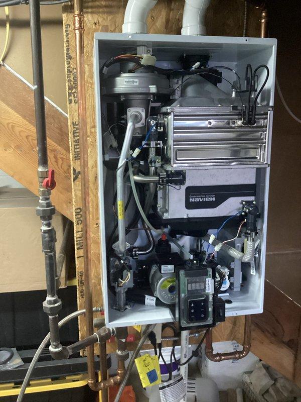 Performed maintenance on Navien tankless water heater experiencing inconsistent heating issues. Conducted descaling procedure on heat exchanger to remove mineral buildup affecting performance. Verified proper venting connections and inspected all plumbing components, restoring unit to optimal operating temperature and efficiency.