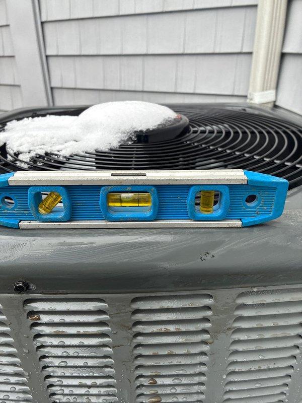 Leveled AC condensing unit that showed significant frost accumulation on the fan component due to improper installation angle. Unit was repositioned on concrete pad to ensure proper drainage and optimal system operation, preventing continued ice buildup that could damage the system.