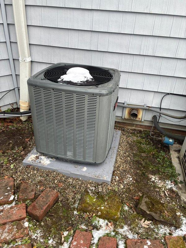 Leveled AC condensing unit that showed significant frost accumulation on the fan component due to improper installation angle. Unit was repositioned on concrete pad to ensure proper drainage and optimal system operation, preventing continued ice buildup that could damage the system.