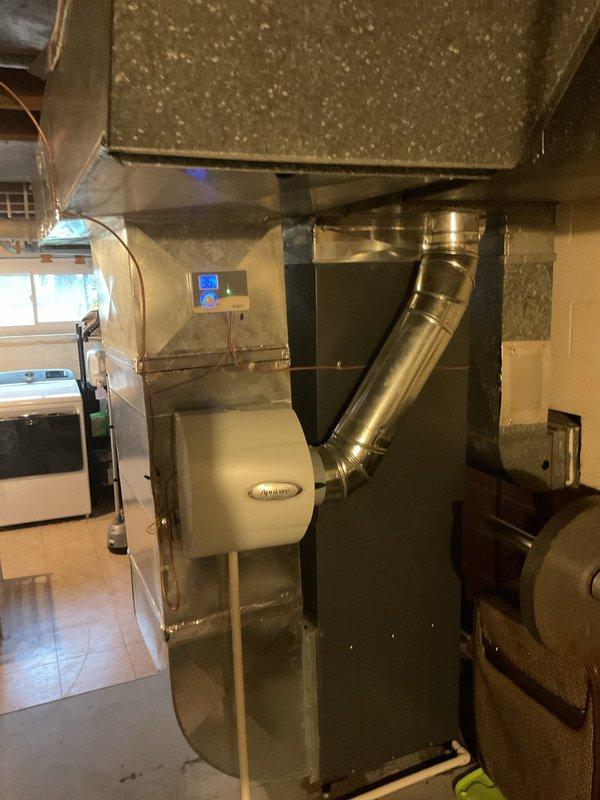 Performed routine maintenance on a 5-year-old gas furnace with attached Aprilaire humidifier. Inspected ductwork system, control panel, and exhaust venting in basement installation. System appears to be functioning properly with some dust accumulation noted on components.