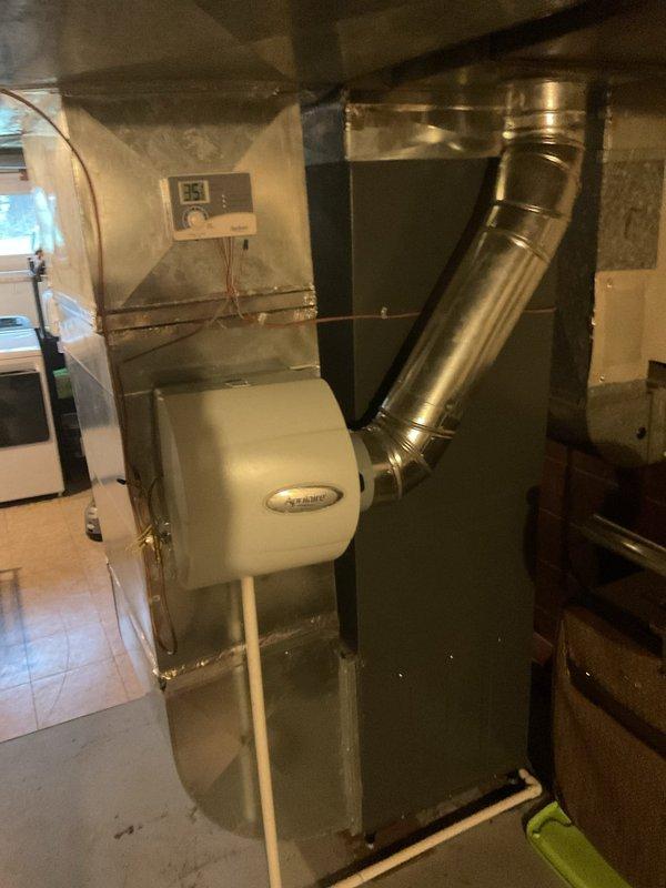 Performed routine maintenance on a 5-year-old gas furnace with attached Aprilaire humidifier. Inspected ductwork system, control panel, and exhaust venting in basement installation. System appears to be functioning properly with some dust accumulation noted on components.