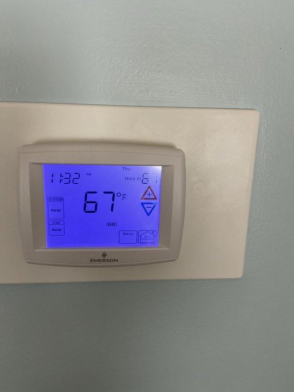 Performed comprehensive winter heating tune-up on aging furnace system located in basement utility area. Inspected unit showing normal wear with some discoloration on upper cabinet section. Verified proper operation of Emerson programmable thermostat (currently set at 67°F in Heat mode) and confirmed system cycling appropriately.